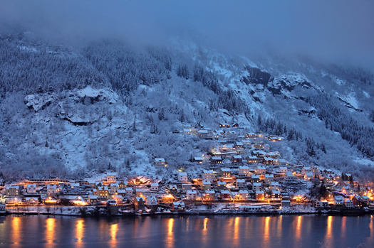 A snow covered hillside by a lake